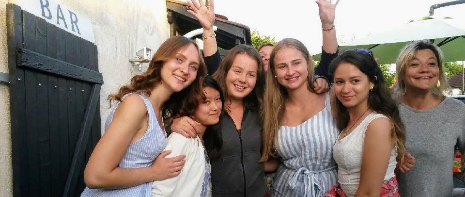 Jeunes filles venues de Lettonie, Norvège, Venezuela, Finlande et Japon partageant un repas convivial — amitié, diversité et découvertes culturelles à l’origine de notre projet