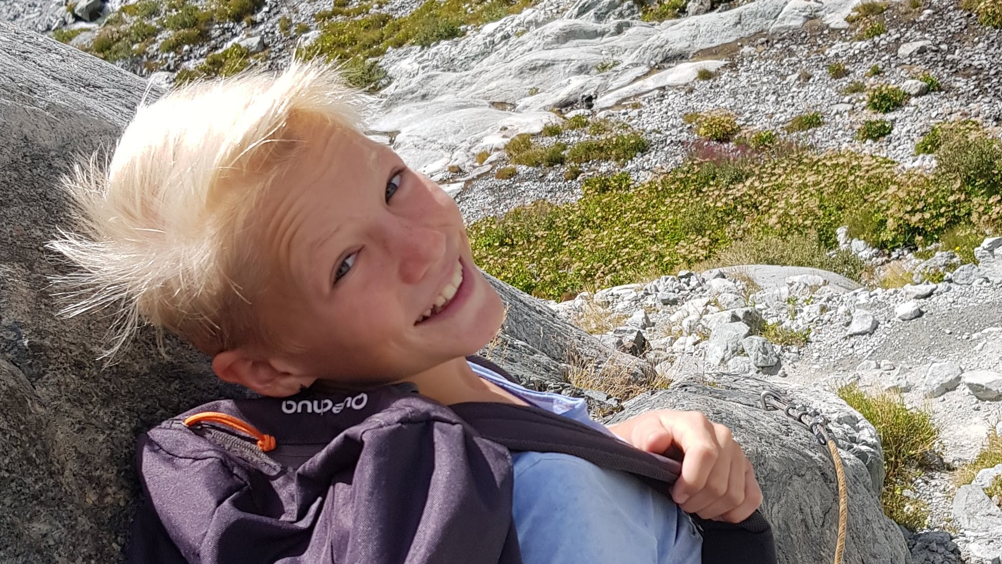 Jeune voyageur français souriant lors d’une randonnée en montagne — symbole de liberté, d’aventure et d’ouverture culturelle avec Coco Swap